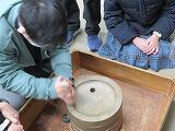 大豆を入れた石臼を挽く生徒